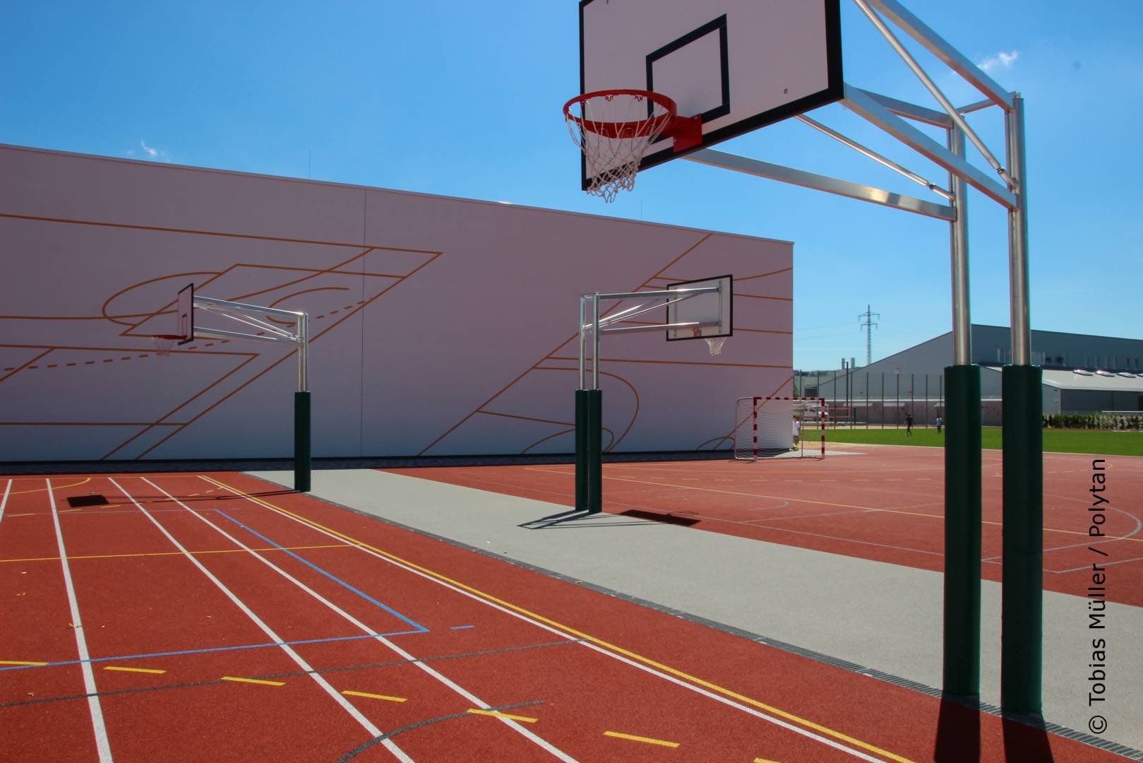 Zwei Basketballfelder ergänzen die Sportanlagen auf der Rückseite der Dreifachsporthalle. Als Kunststoffbelag entschieden sich die Planer für den wasserdurchlässigen PolyPlay S – ein universal einsetzbarer Sportboden mit glatter Oberfläche und einem sehr guten Ballsprungverhalten. 