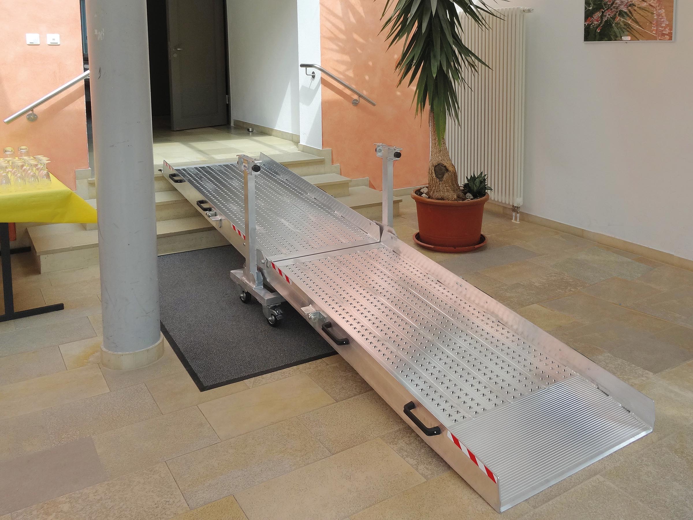 Die zusammenklappbare Rampe mit integriertem rollbaren Unterbau ermöglicht Rollstuhlfahrern einen einfachen Zugang.